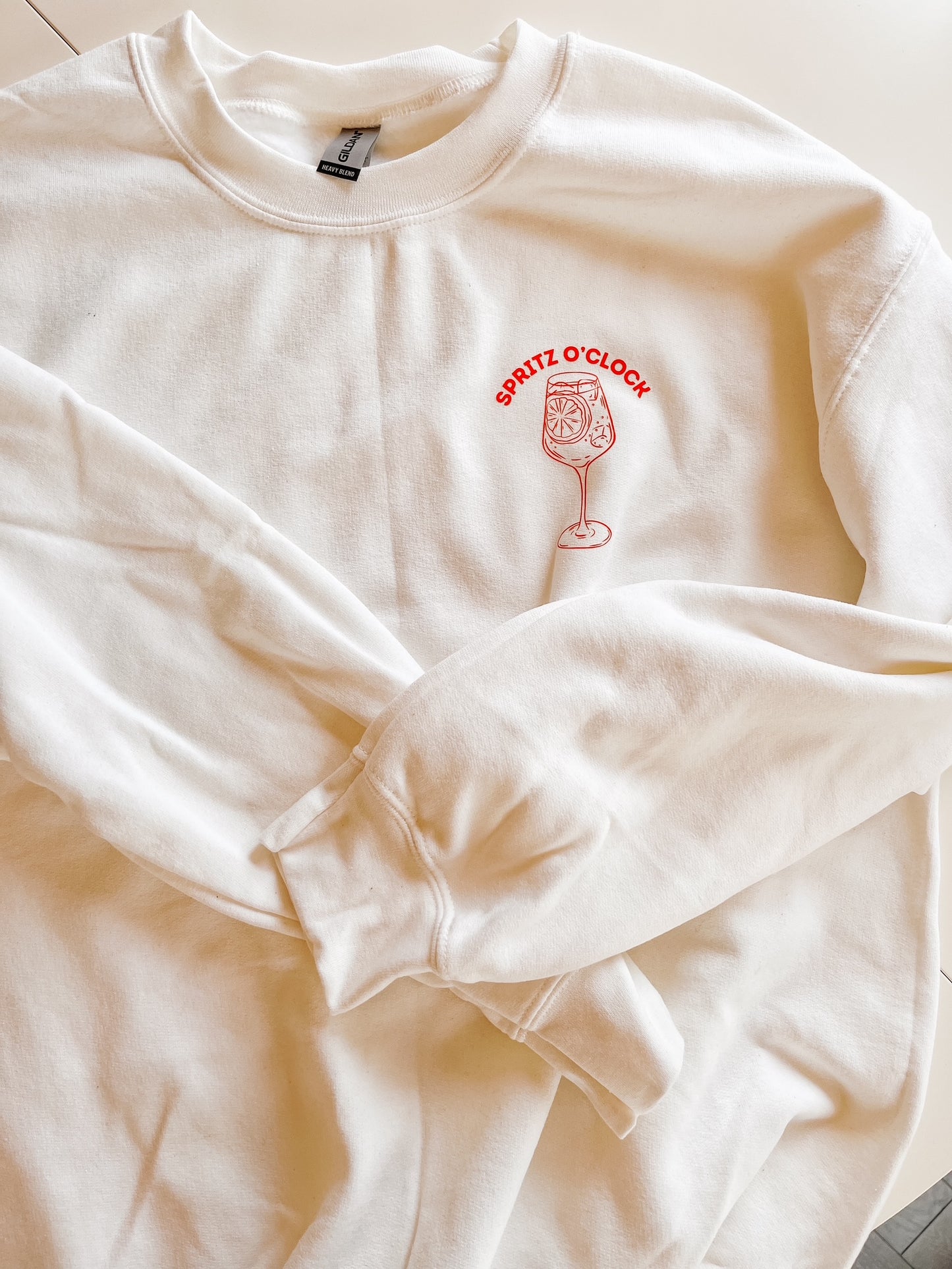 White crewneck sweater with orange logo on white background