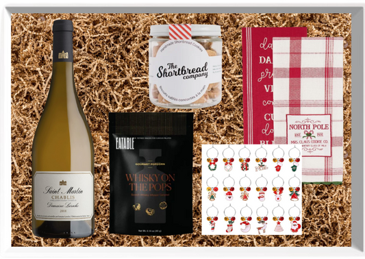 Gift set with wine, snacks, and decorative items on a textured surface